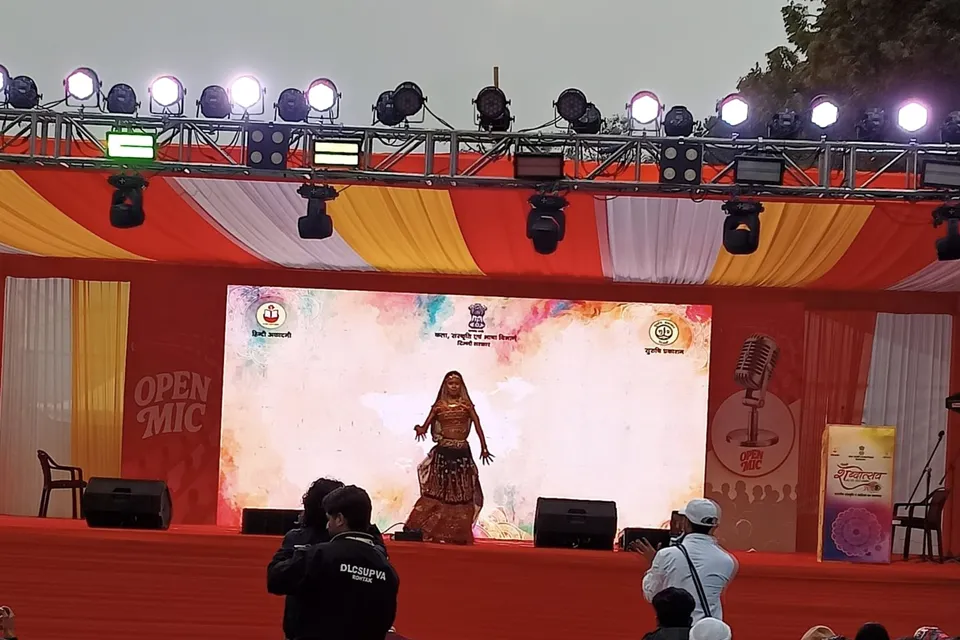 A dancer performs on the open-air stage as the audience watches