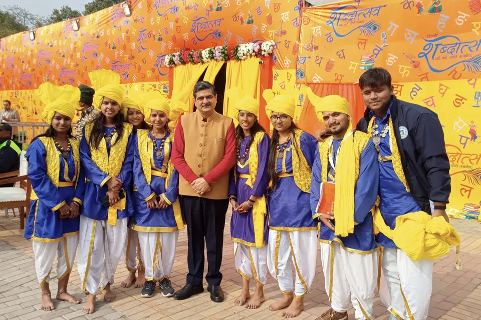 A folk troupe in blue and yellow poses with organisers