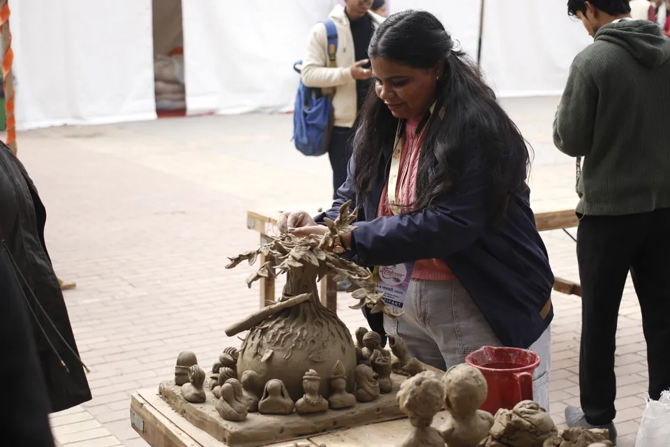 A sculptor shapes a clay figure outdoors