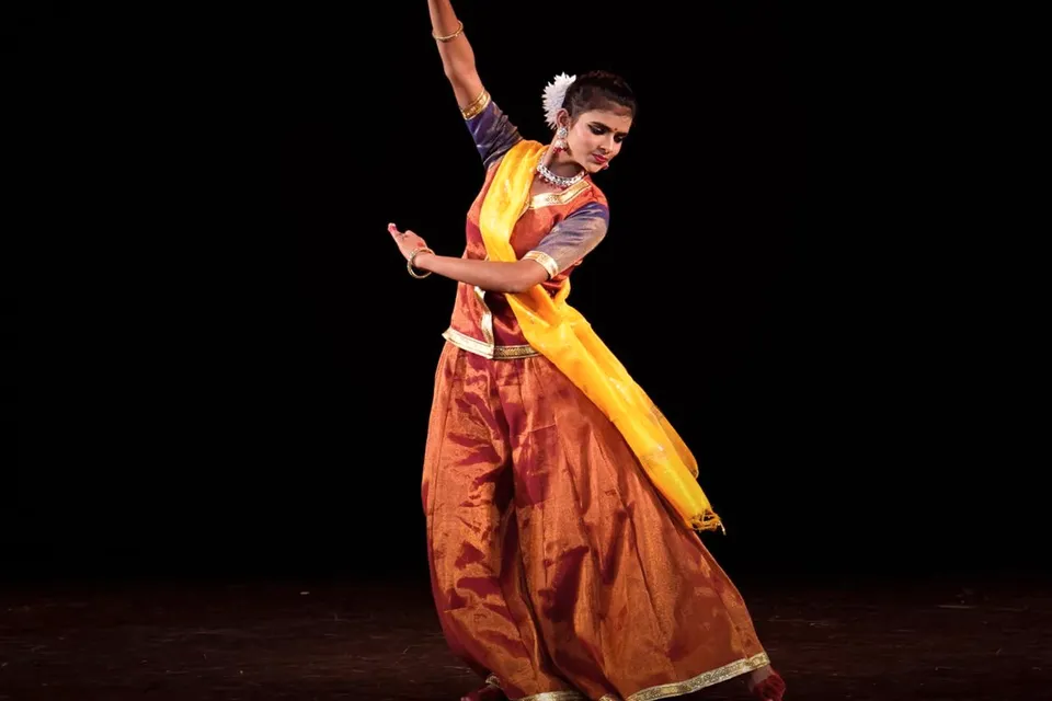 A classical dancer in saffron and gold mid-pose