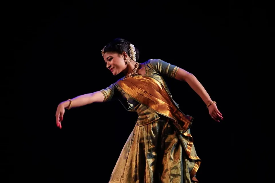 A solo dancer in a gold-bordered saree