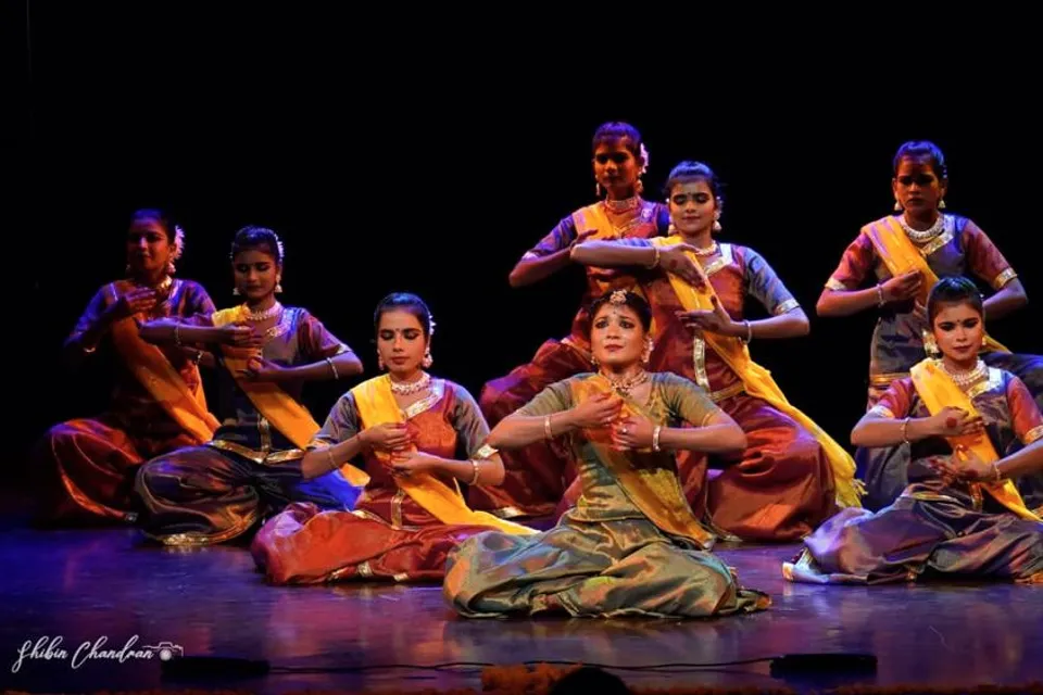 Dancers seated in a tableau on stage