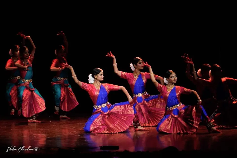 Dancers in pink and blue costumes in formation