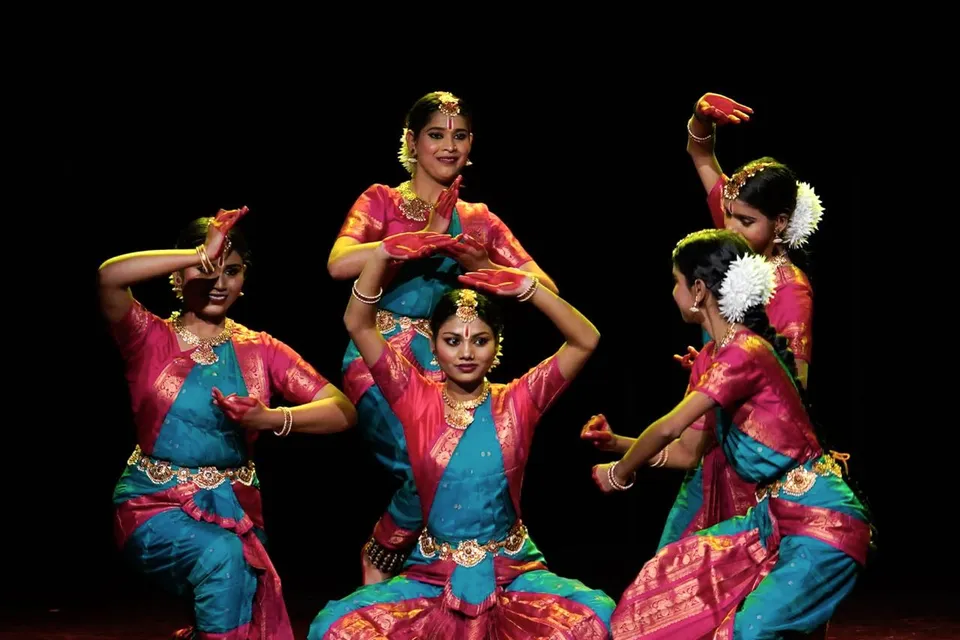 Dancers in pink and teal in a close formation