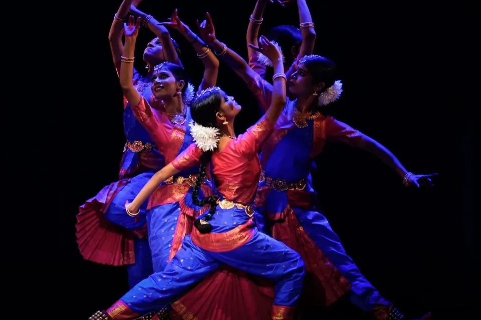 Dancers in blue and pink lit from the side