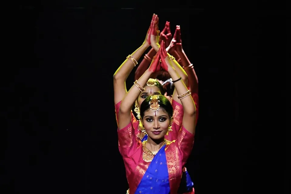 A dancer with hands joined above her head