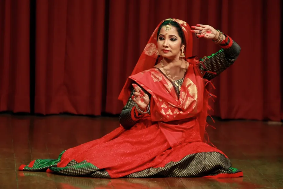 A Kathak dancer in red with raised hands